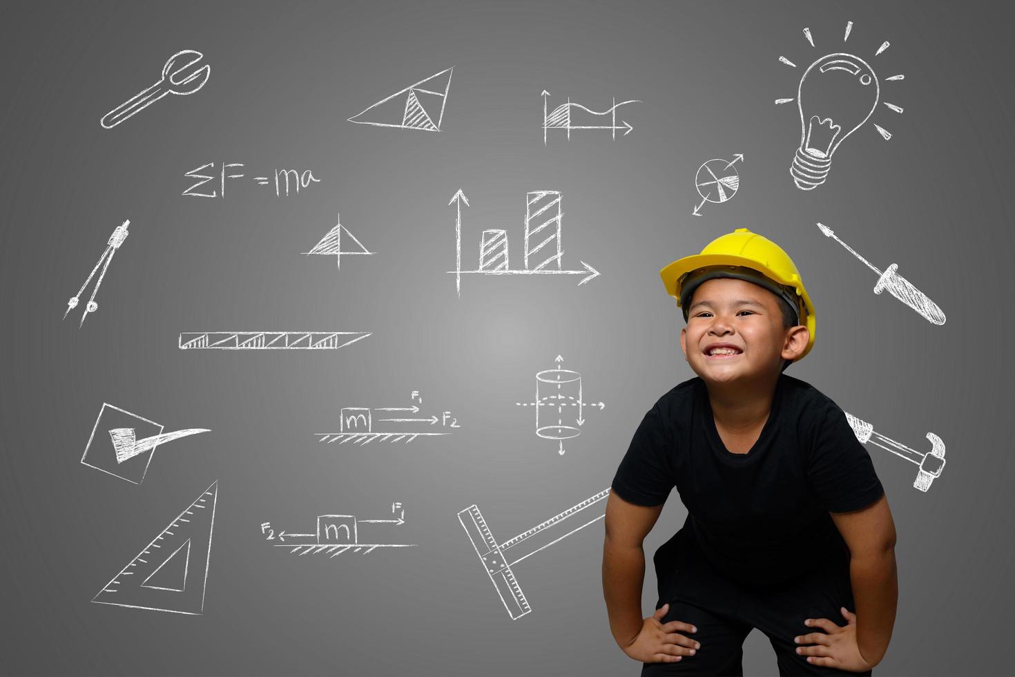 un niño con un sombrero de ingeniero amarillo y un plano de la casa en la pizarra foto