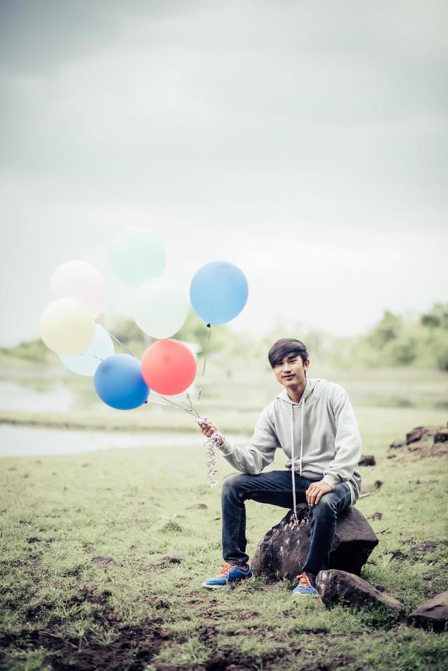 joven sosteniendo globos de colores en la naturaleza foto