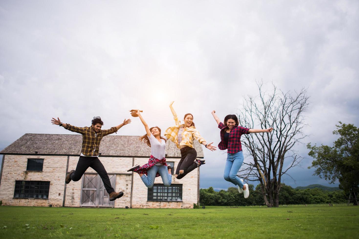 Happy group of teen students jumping in a park together photo