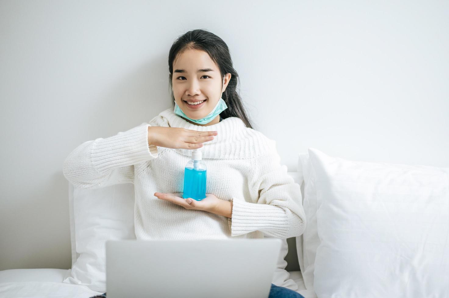 Young woman on bed holding hand washing gel photo