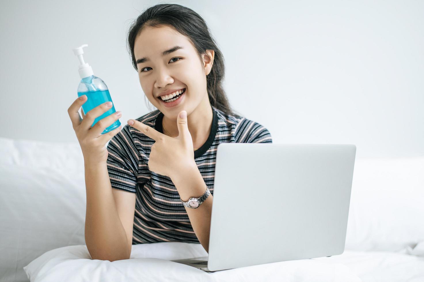 Young woman on bed holding hand washing gel photo