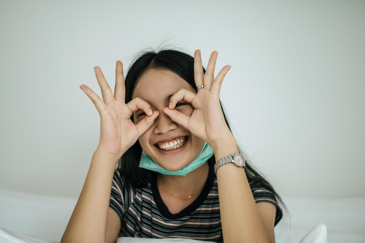 Girl wearing a sanitation mask, striped shirt, and hand symbol okay photo