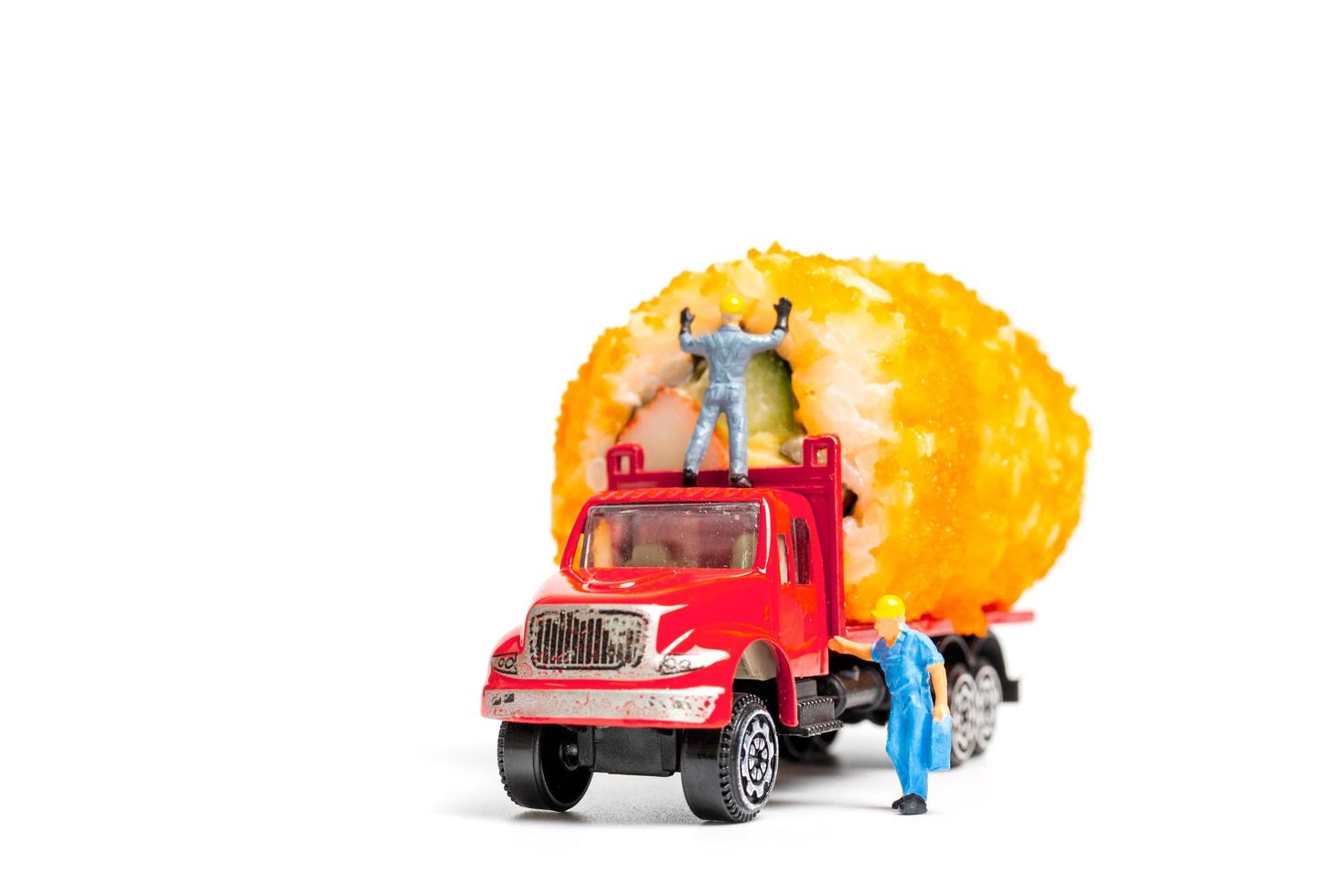 Miniature people hauling a sushi roll on a truck photo