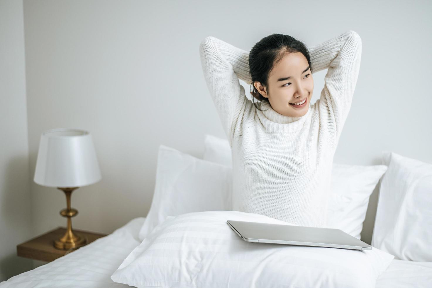 mujer joven, estirar cama, con, computador portatil foto