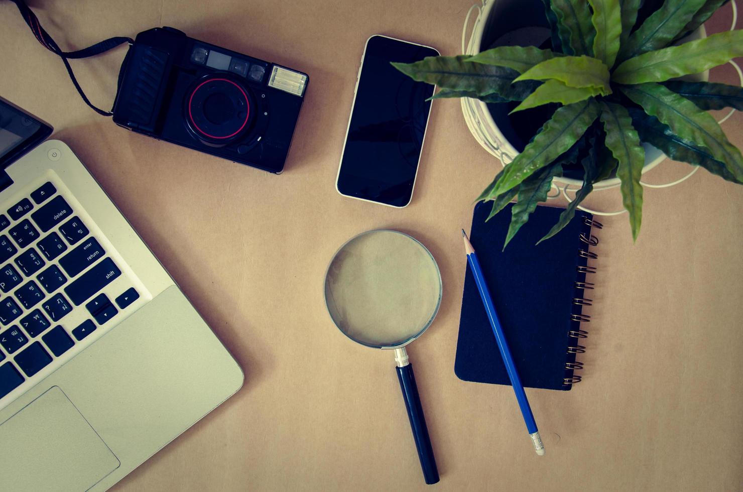 Magnifying glass, camera, and phone on a desk photo