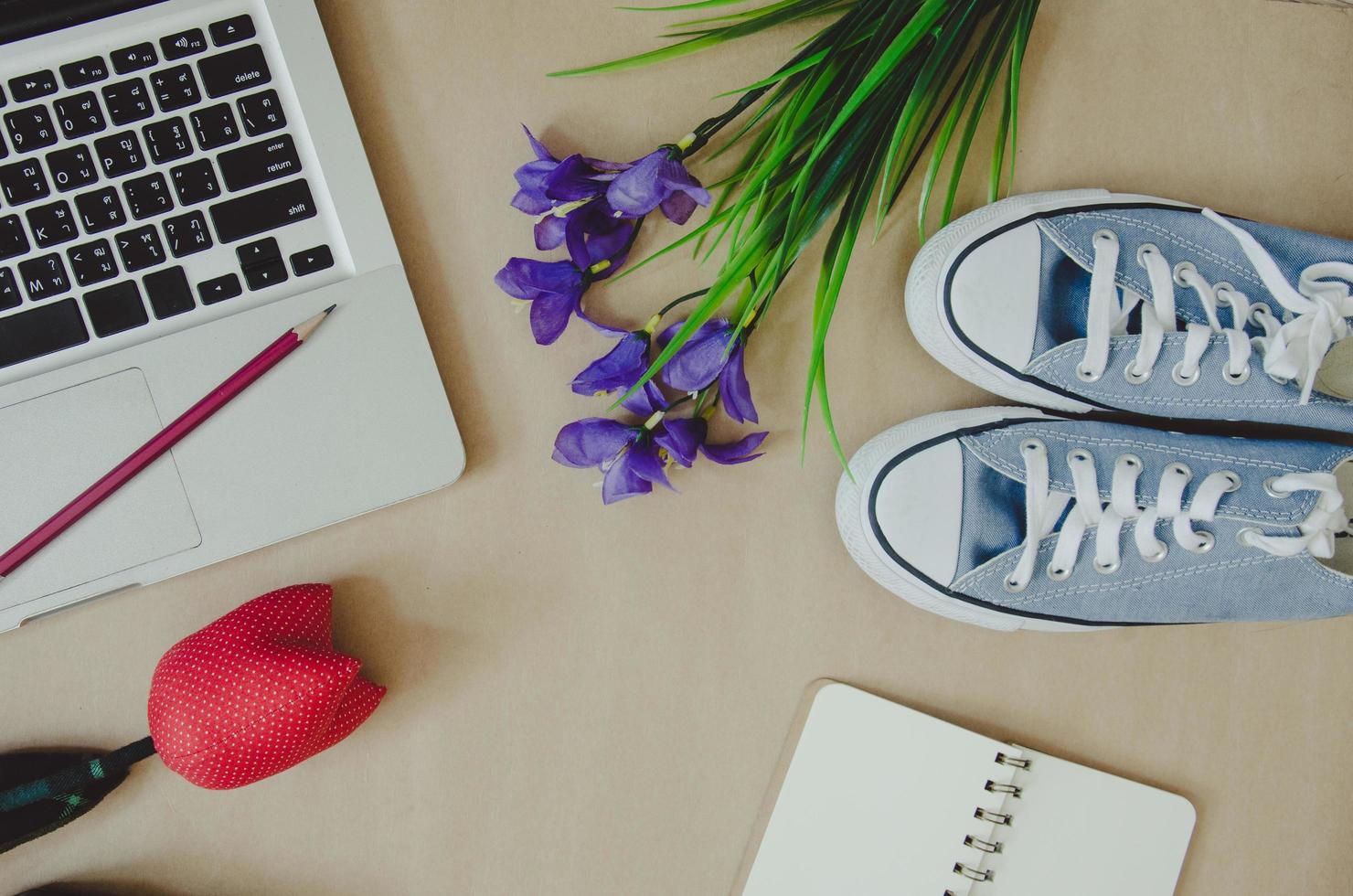 Laptop, shoes, and flowers on brown background photo