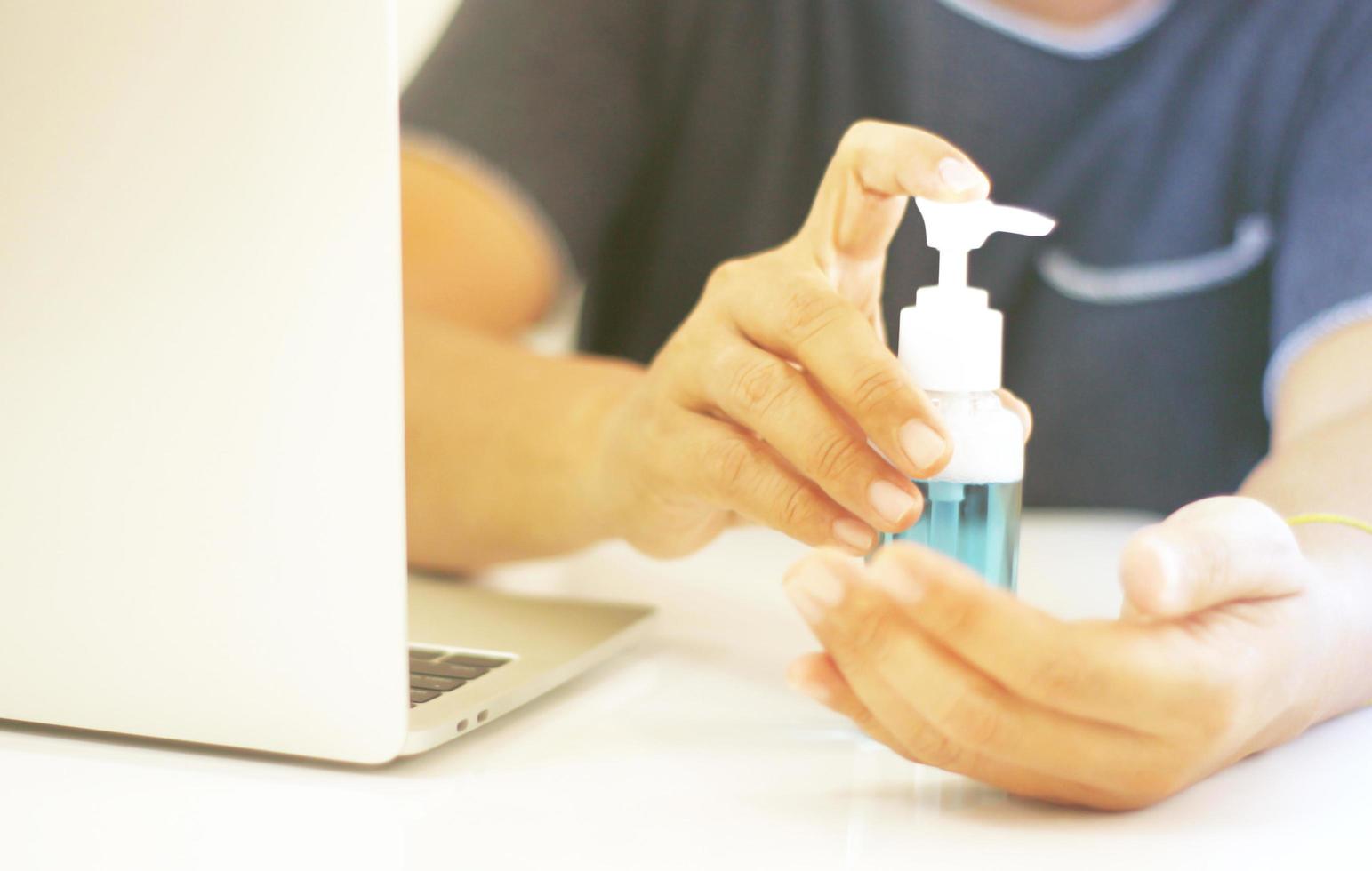 Person applying hand sanitizer at computer photo