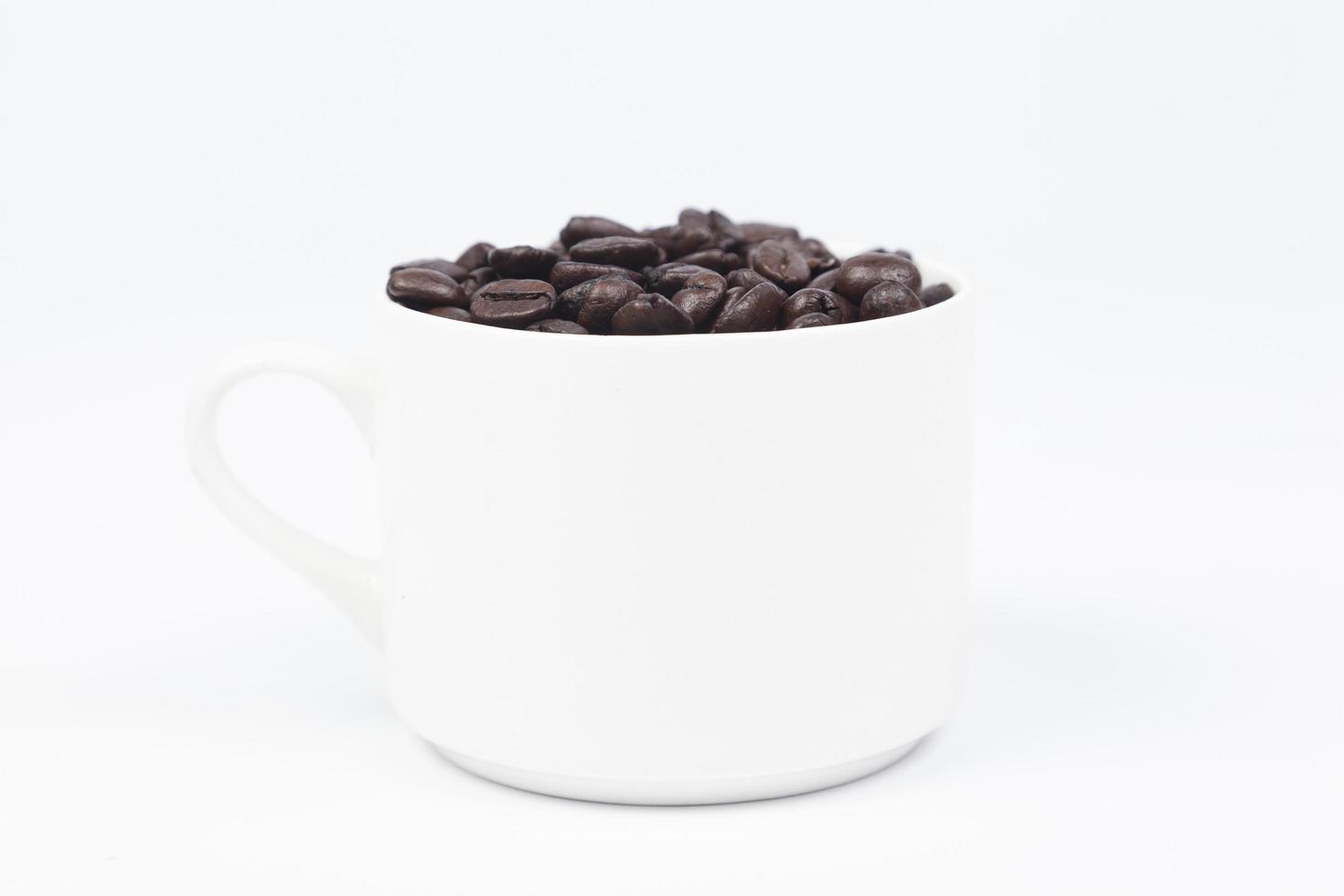 Taza con granos de café sobre fondo blanco. foto