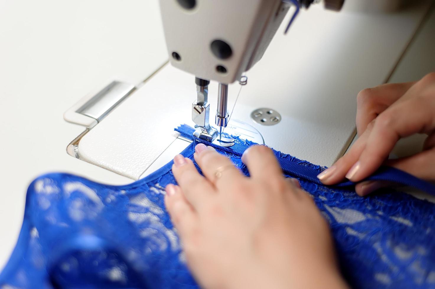 Person sewing blue fabric photo