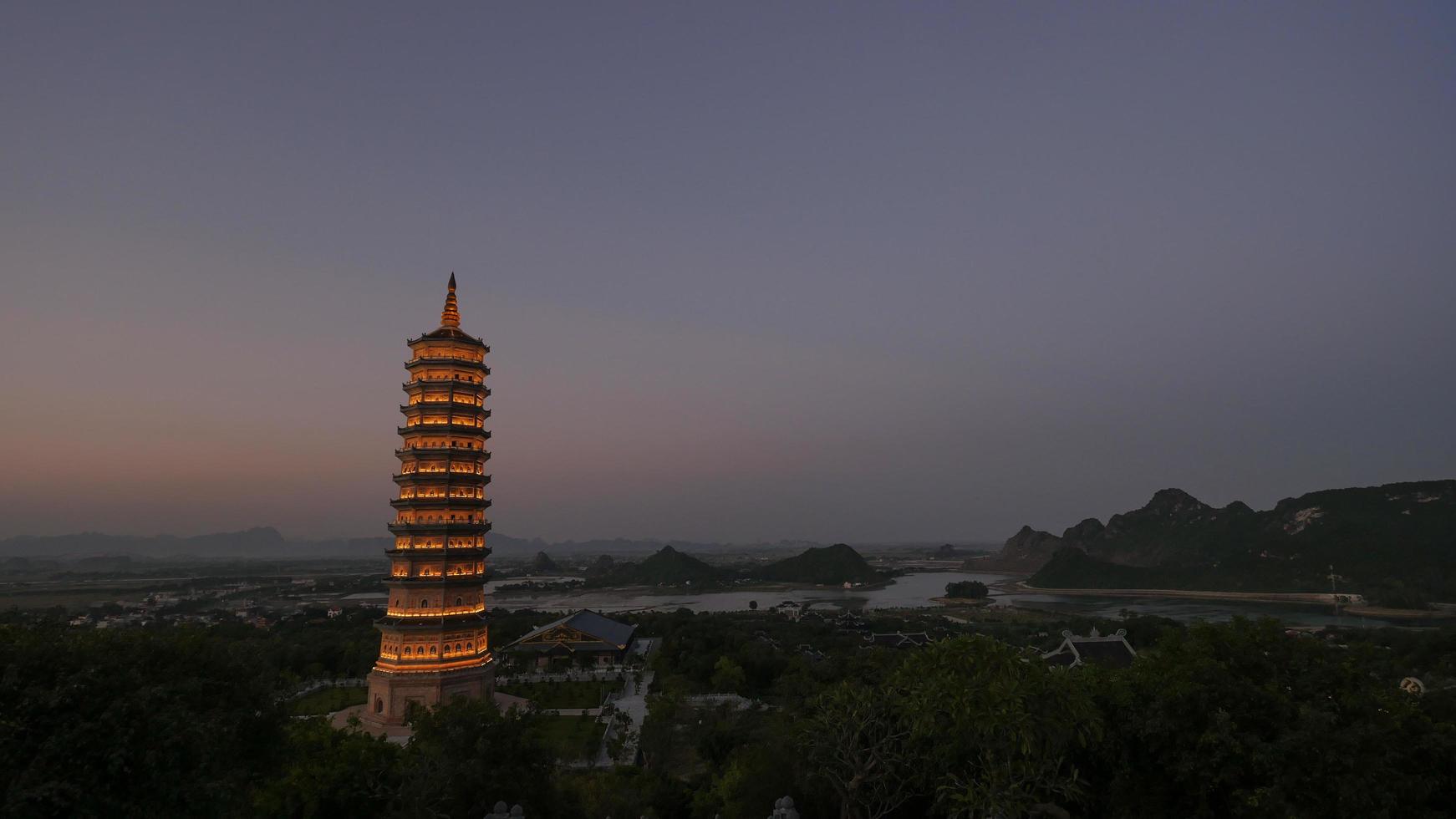 Illuminated Bai Dinh Pagoda tower at dusk photo