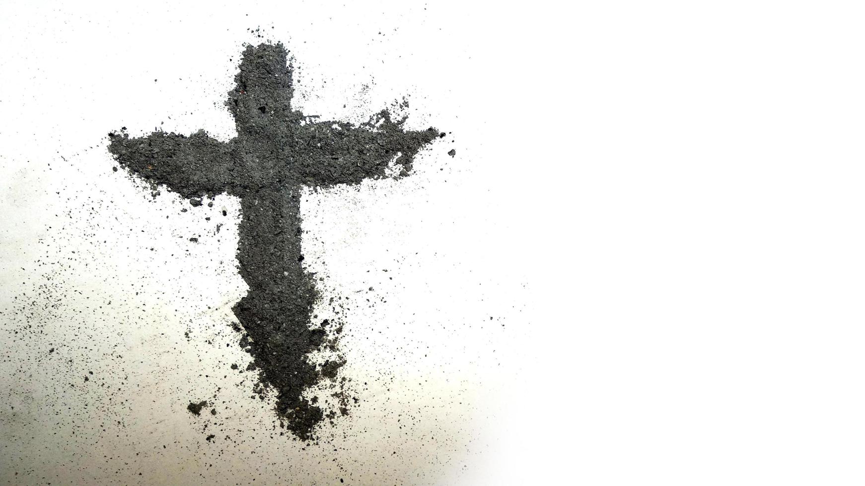 Cross made of ashes on white background photo