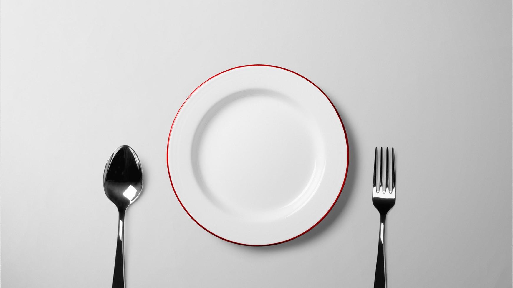 plato, cuchara y tenedor en la mesa blanca foto
