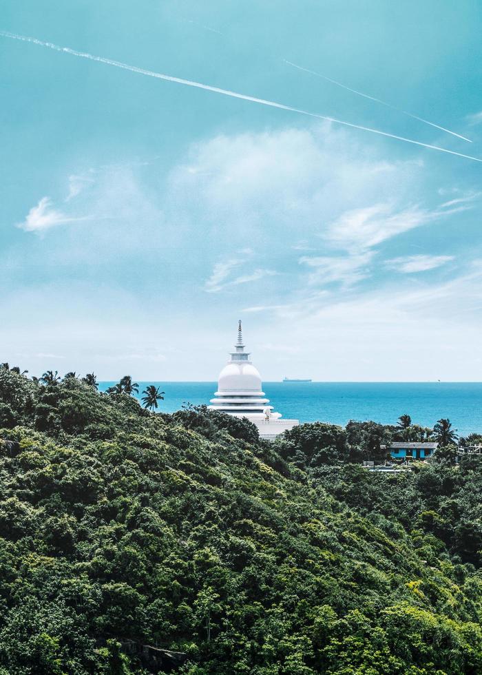 White and blue lighthouse on mountain by body of water photo