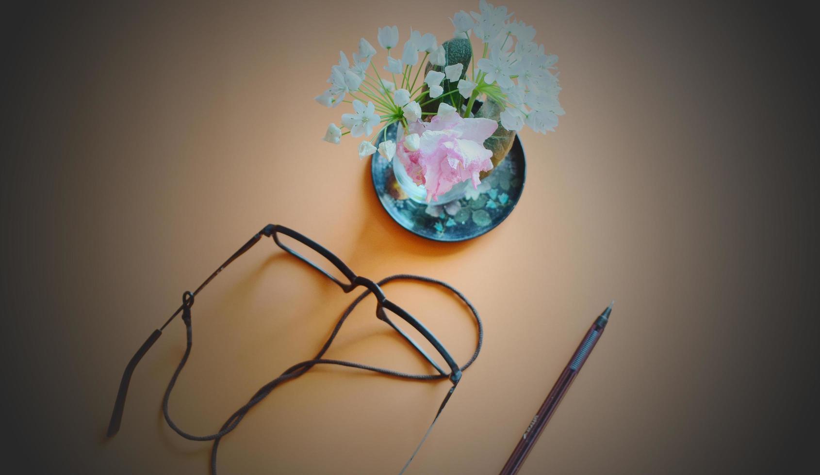 Black eyeglasses and next to blue and white flowers on ceramic plate photo