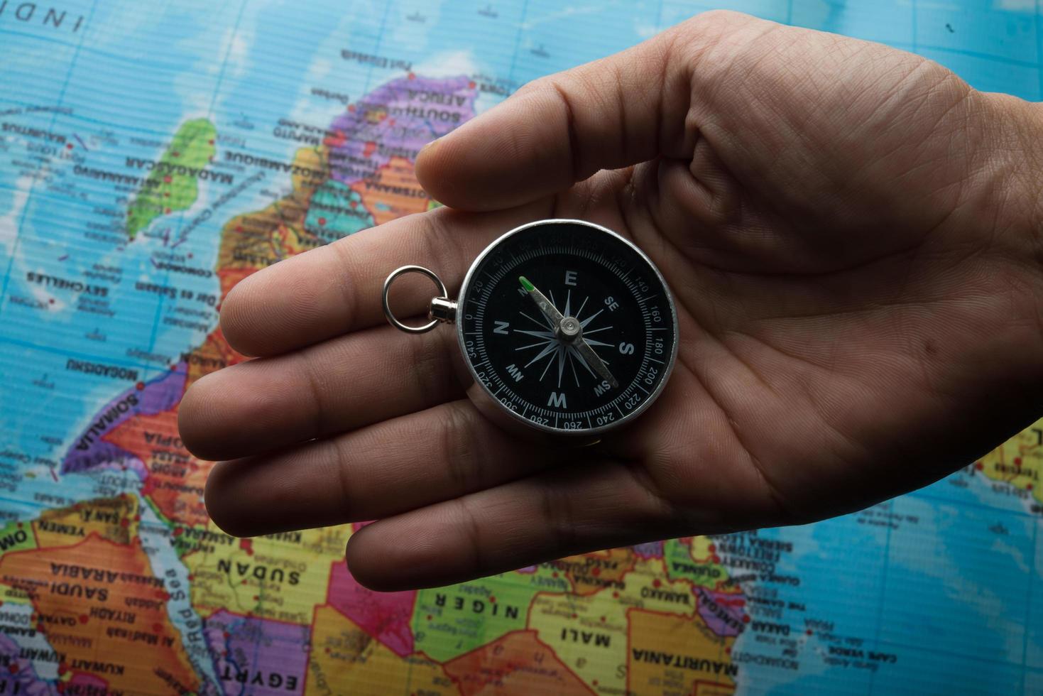 Man holding a compass on top of a map photo