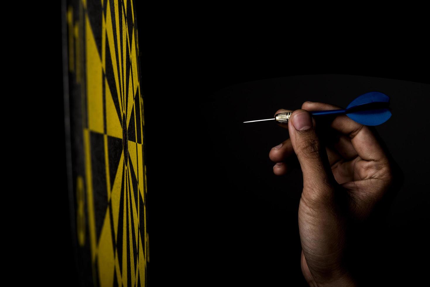 Dartboard with arrow on black background, success concept photo
