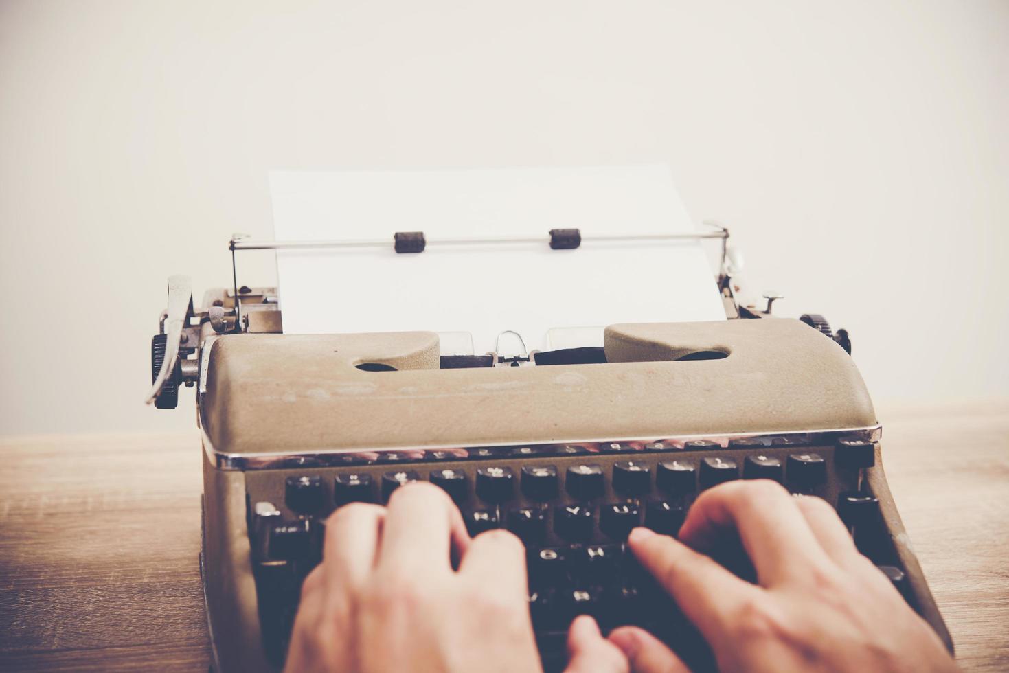 Manos escribiendo en máquina de escribir vintage sobre mesa de madera foto