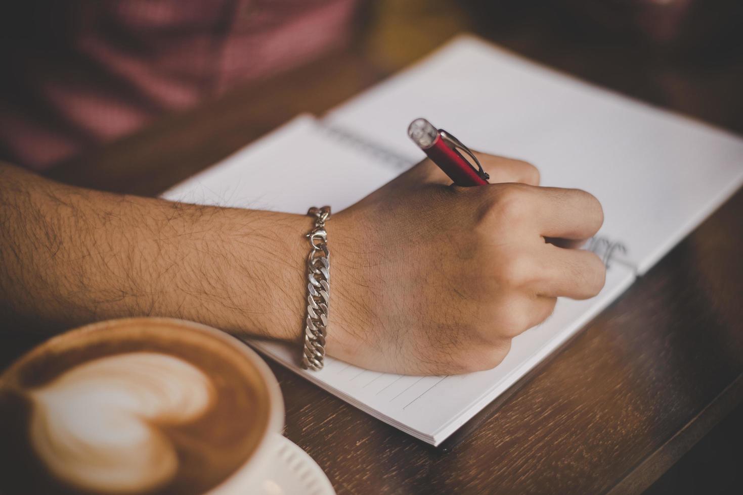 una taza de café en la barra de madera junto a un hipster en un café foto