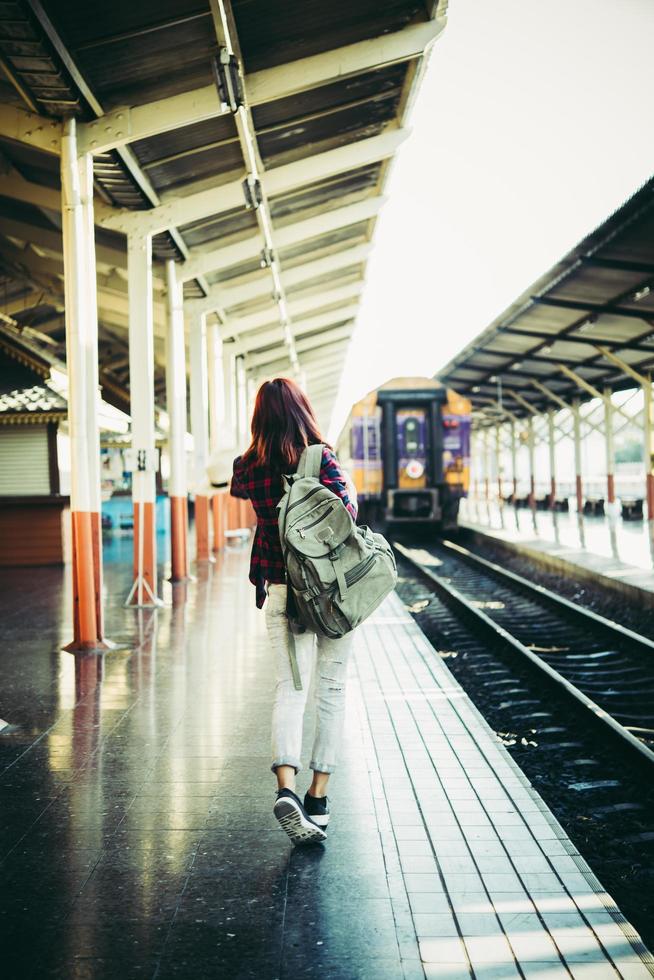 Young hipster woman waiting on the station platform with backpack photo