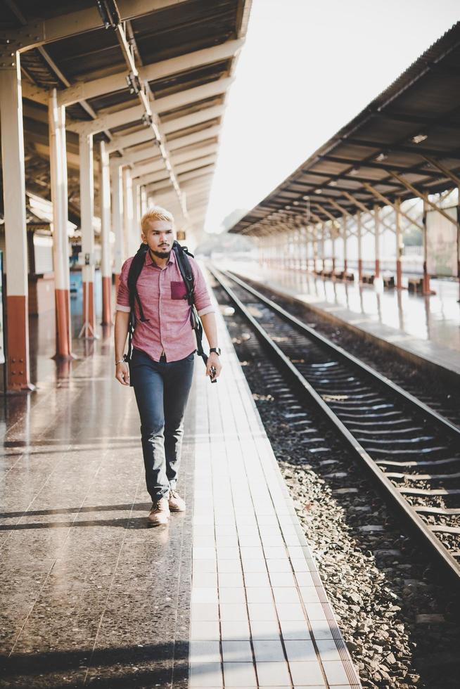 Young hipster man waiting on the station platform with backpack photo