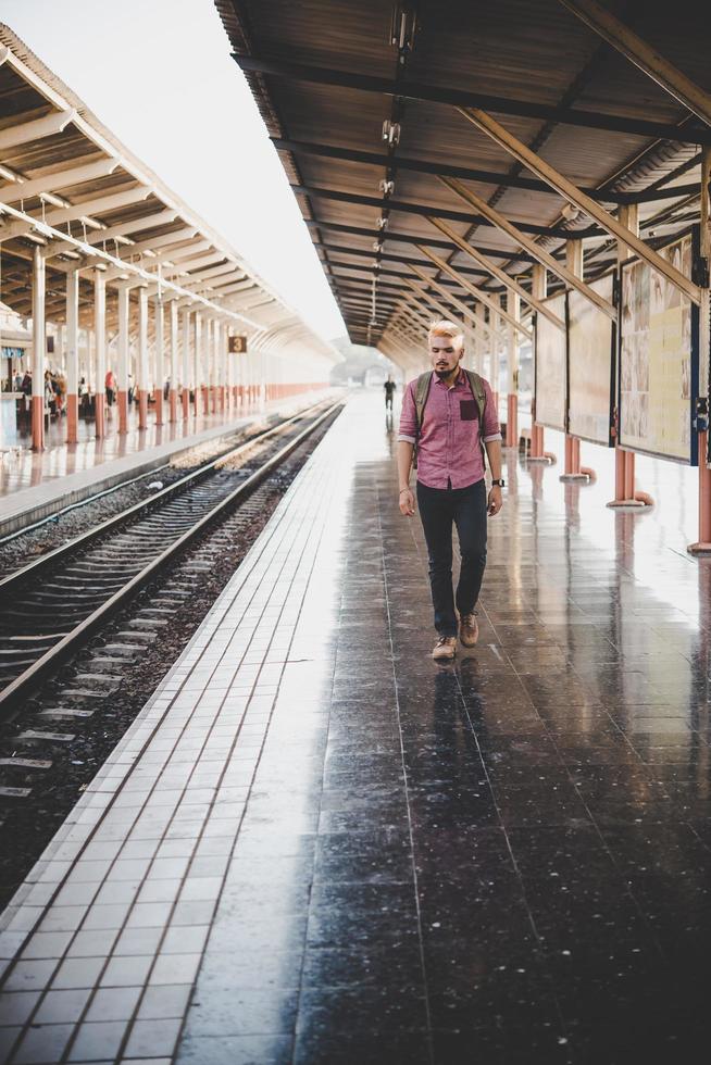 joven inconformista caminando por la estación de tren foto