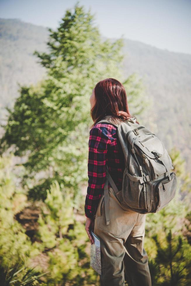 Mujer joven viajero con mochila de pie sobre una montaña foto