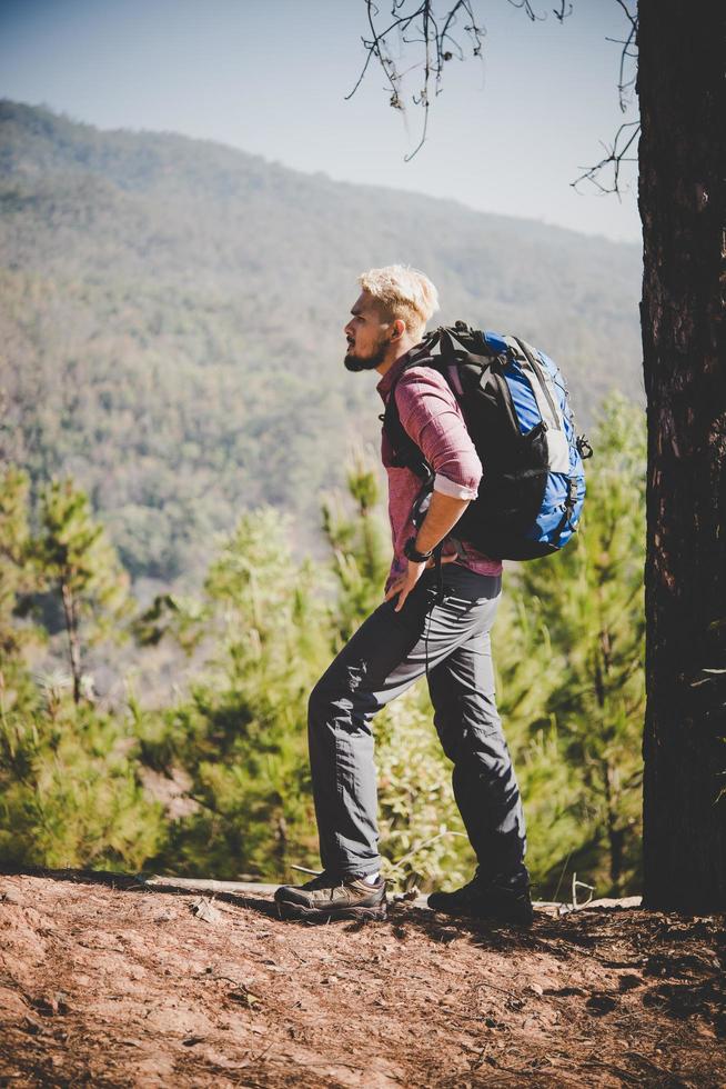 Hiker with big traveling backpack traveling to the mountain photo