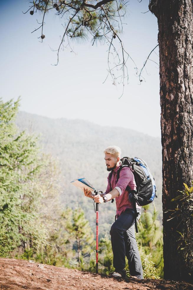 excursionista con mapa y mochila grande viajando a la montaña. foto