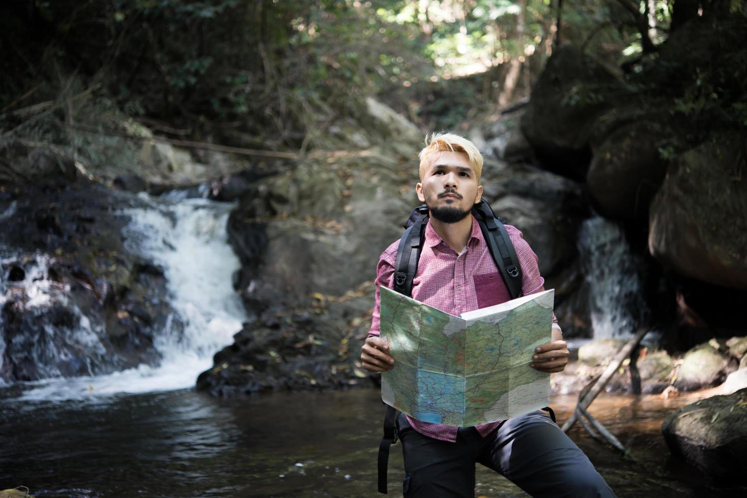 Hombre de aventuras observando el mapa en un camino de montaña foto