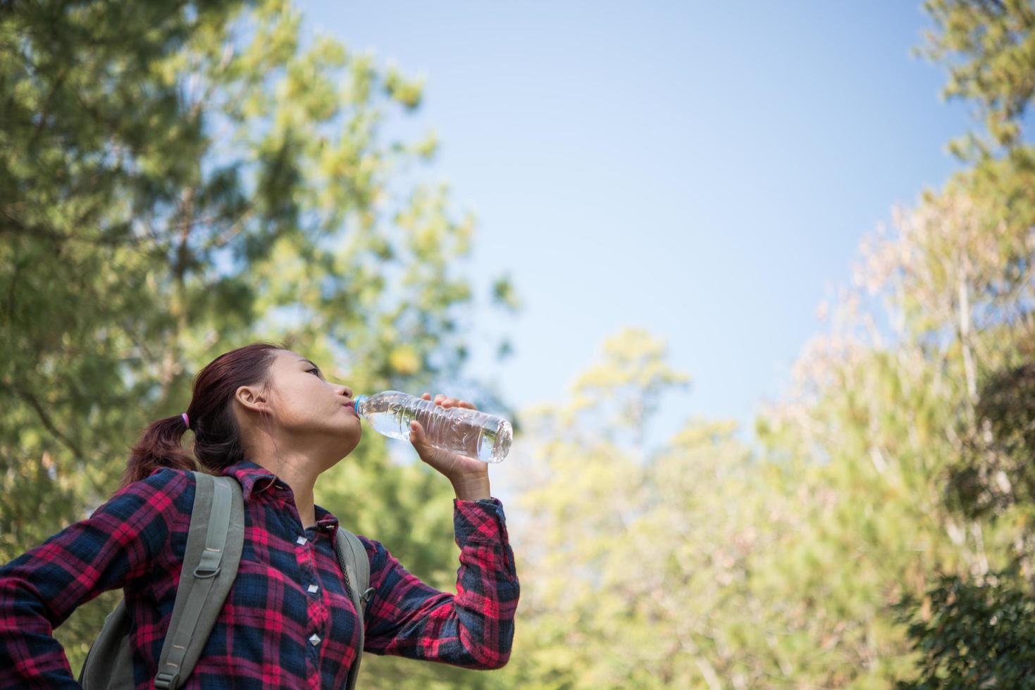 turista mujer feliz con mochila agua potable en la naturaleza foto