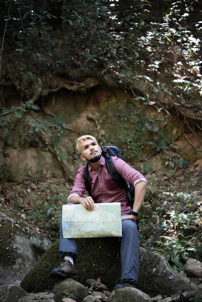 Young tired hiker with backpack sitting in forest photo