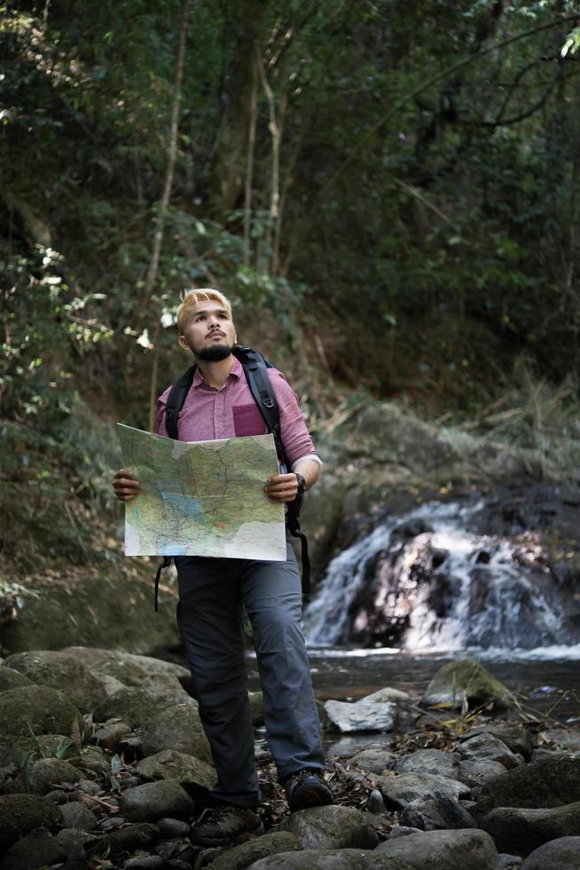 Adventure man observing map on a mountain path photo