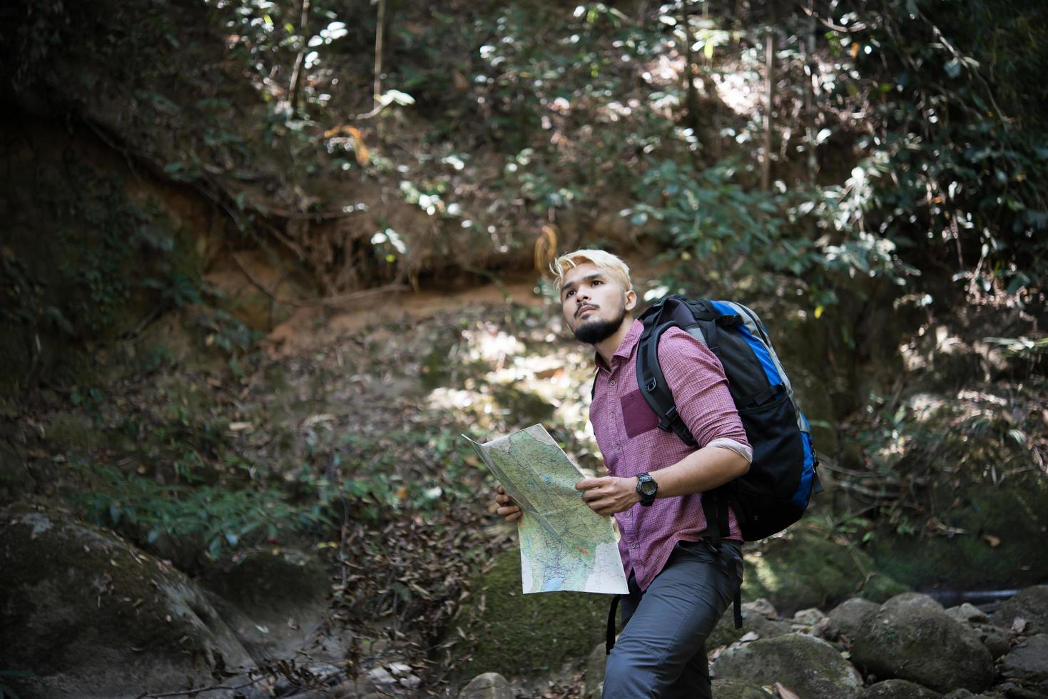 Hombre de aventuras observando el mapa en un camino de montaña foto