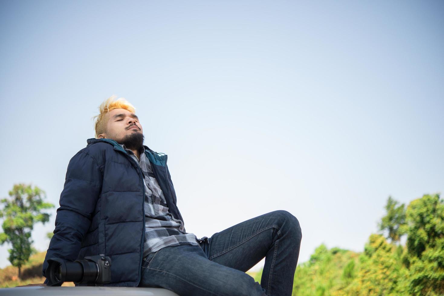 Young hiker enjoying nature sitting on his truck photo