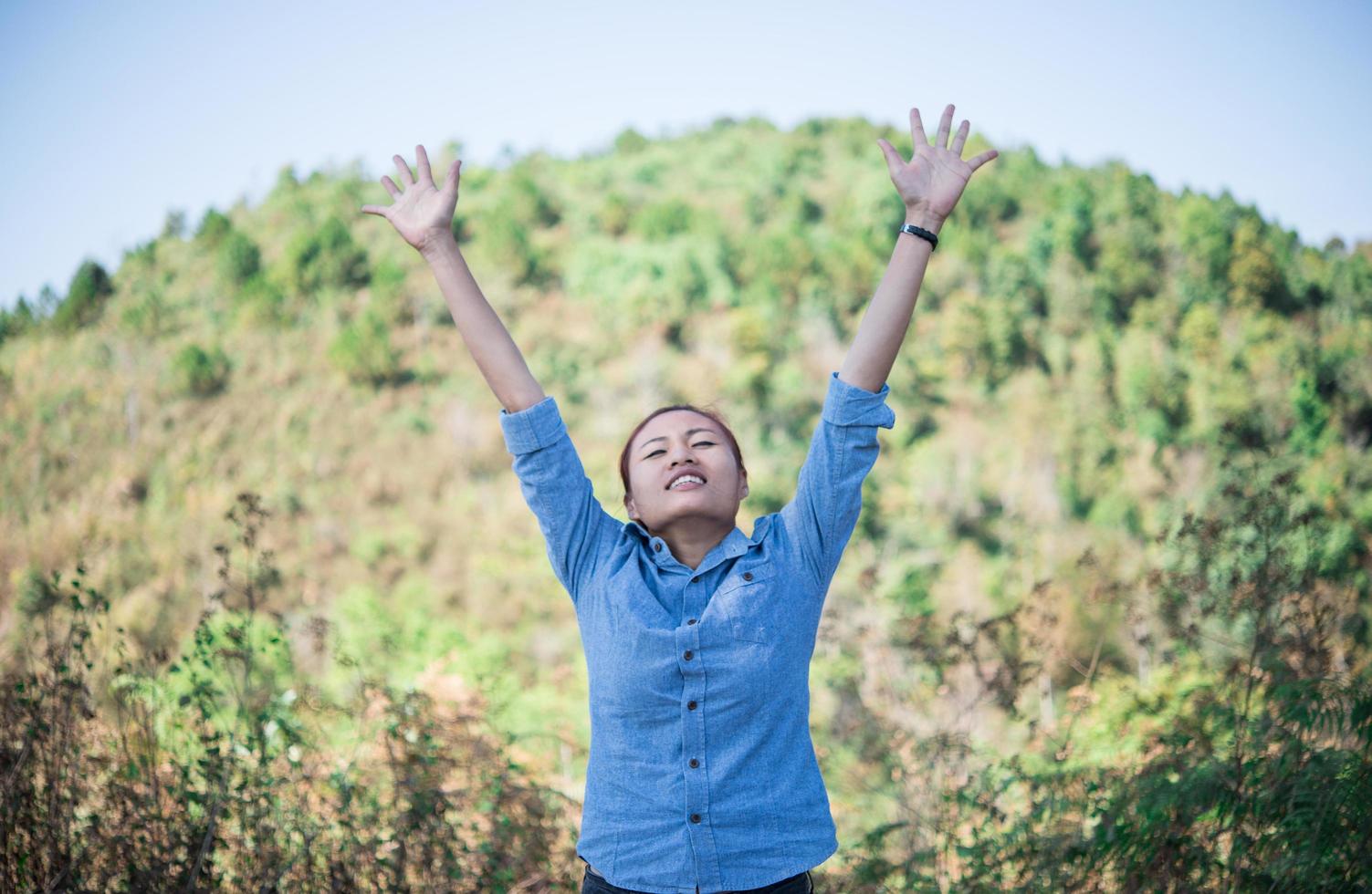 Young woman standing looking to the sky with raised hands photo