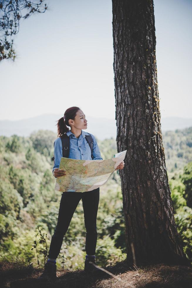 Young woman backpacker hiker reading map hiking trip. Relaxing on holiday. photo