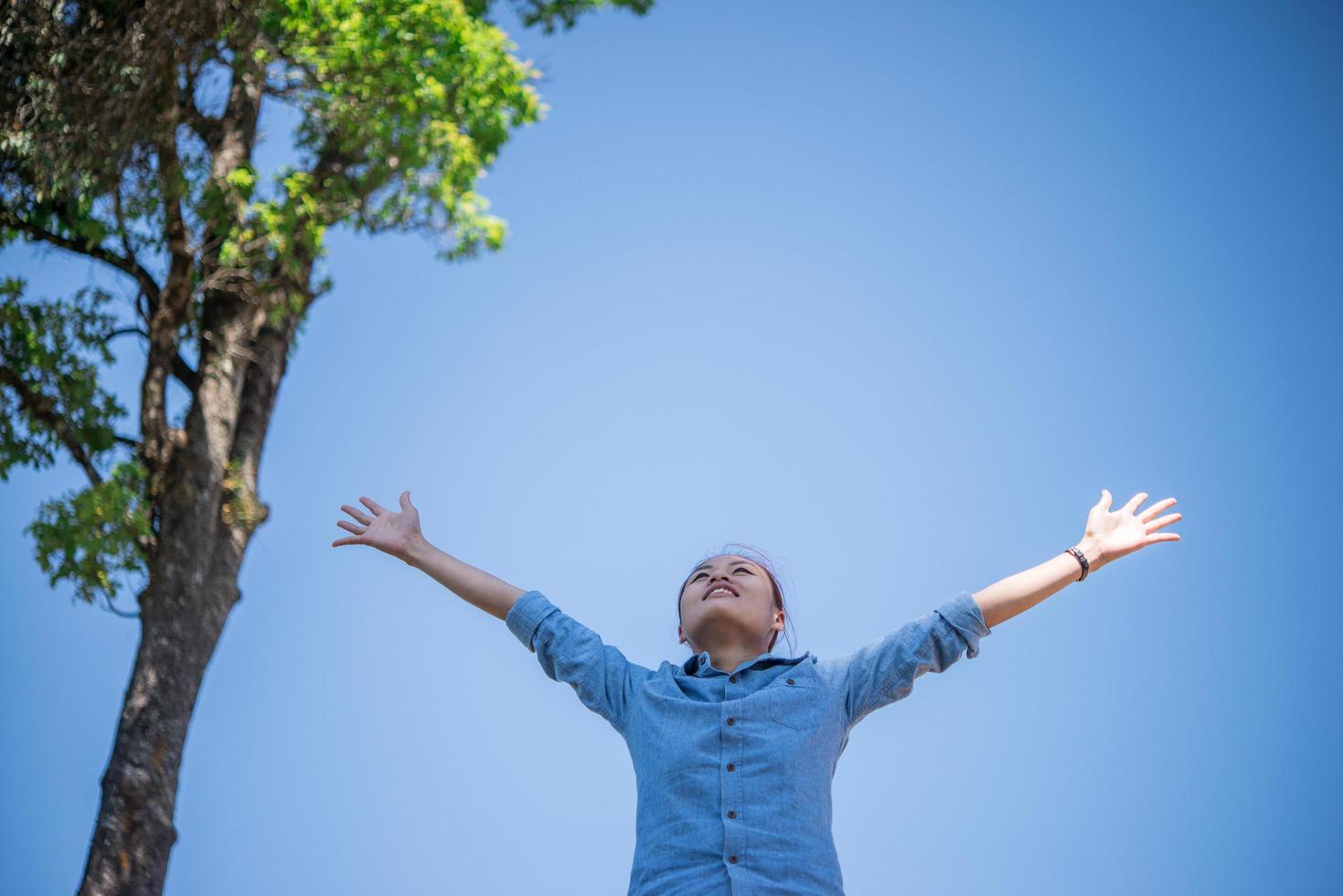 mujer joven de pie mirando al cielo con las manos levantadas foto