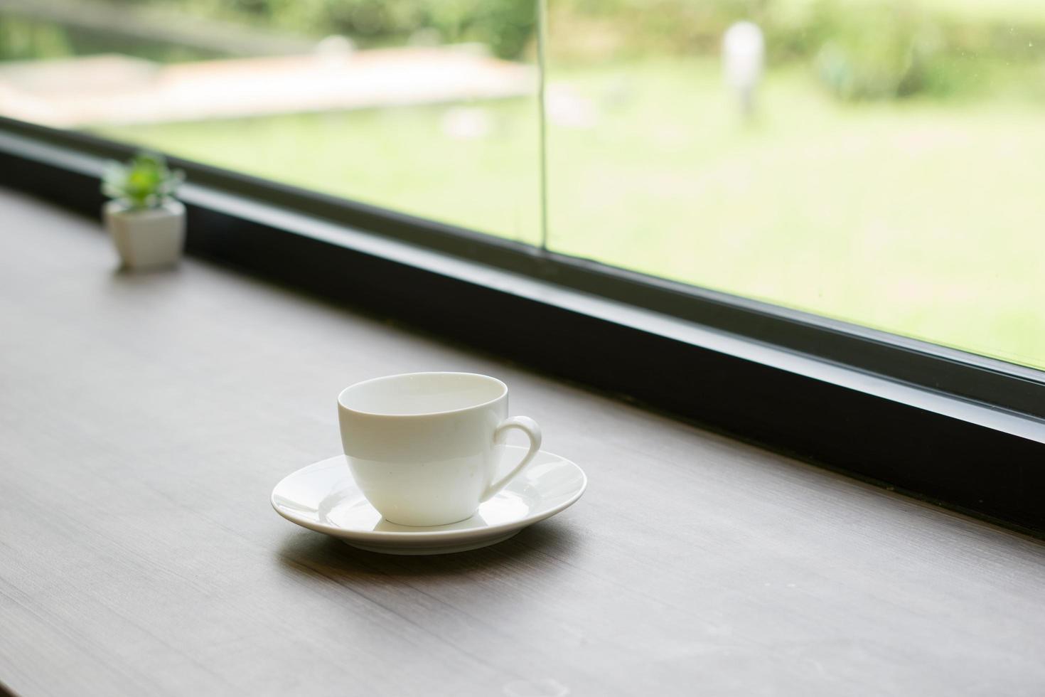 Close-up of coffee cup on a wooden table near a window in the morning photo