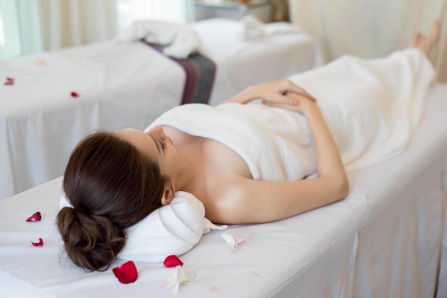 Bella mujer sonriente con flores descansando en el spa antes del masaje foto