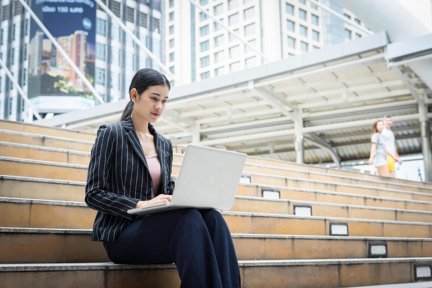 Business woman using laptop sits on the steps. Business people concept. photo