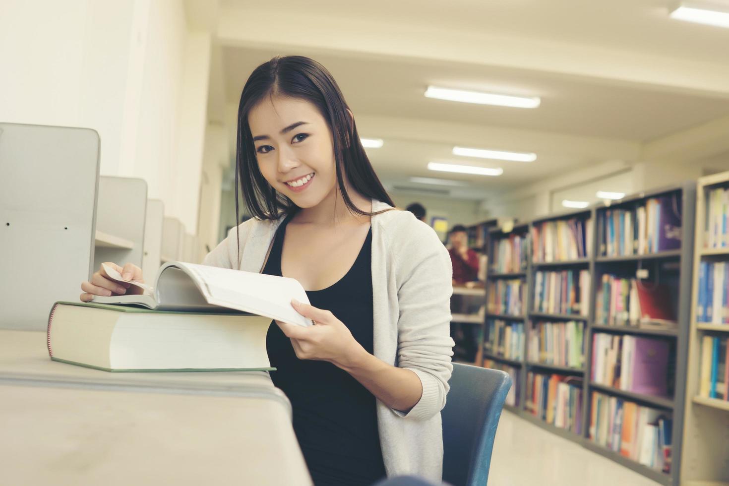 Young Asian student at the library reading a book photo