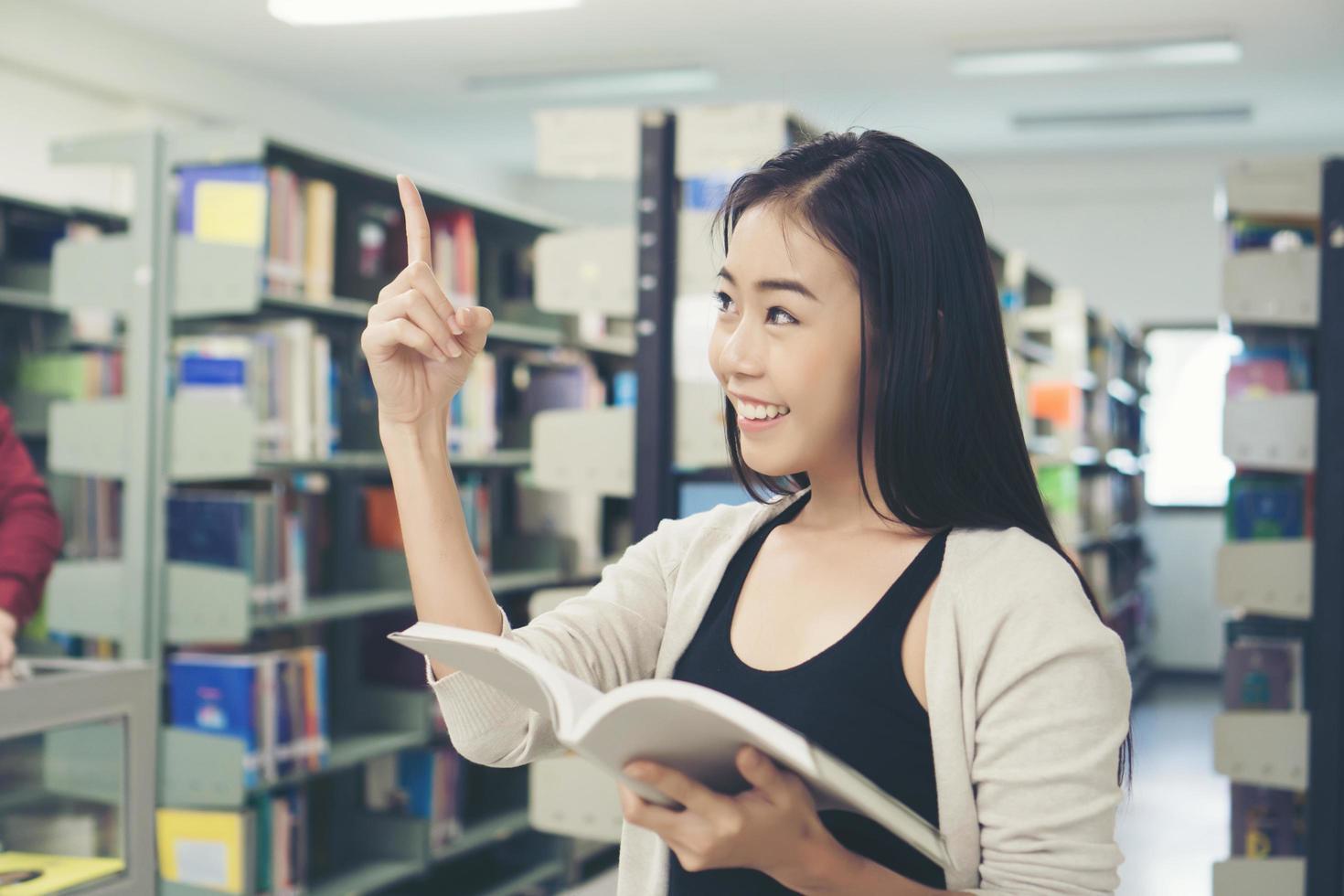 joven estudiante asiático en la biblioteca leyendo un libro foto