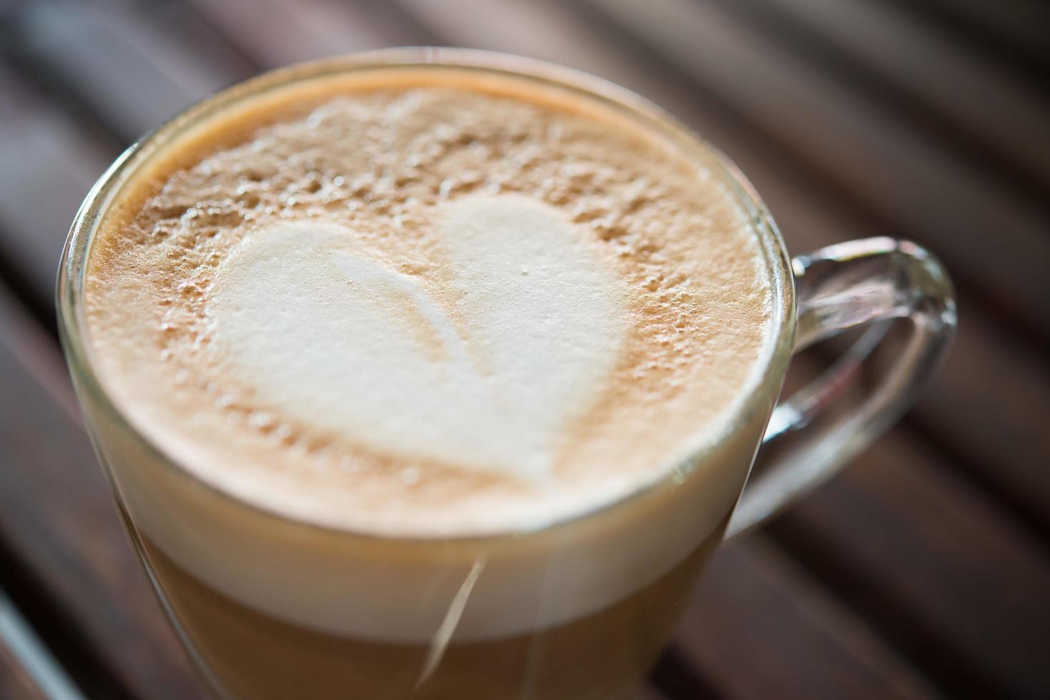 Close-up de taza de capuchino con patrón de leche en forma de corazón en el cafe foto