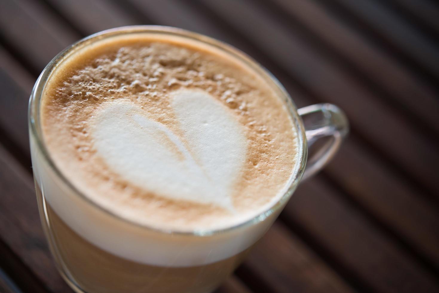 Close-up de taza de capuchino con patrón de leche en forma de corazón en el cafe foto