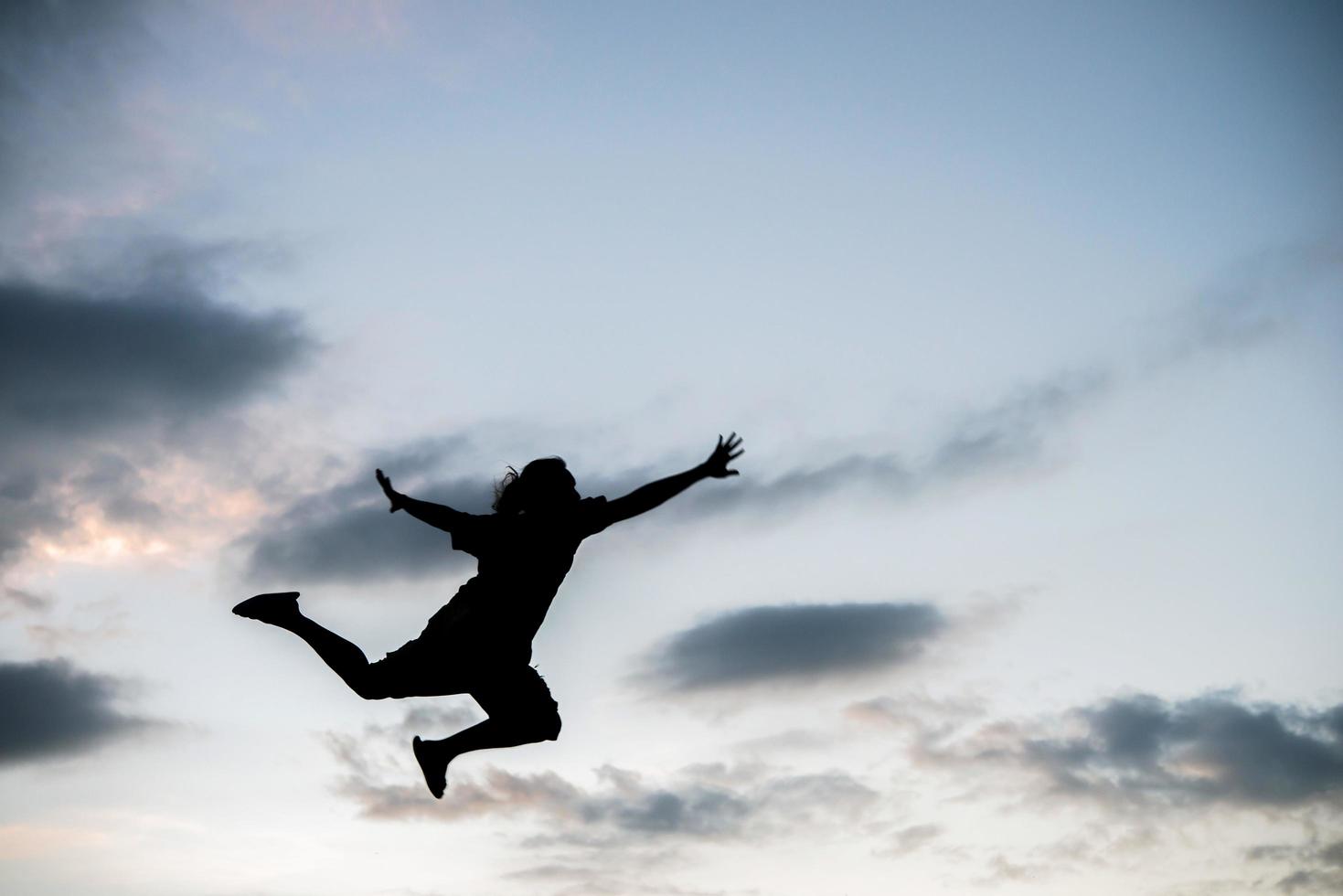 Happy young woman jumping against beautiful sunset photo