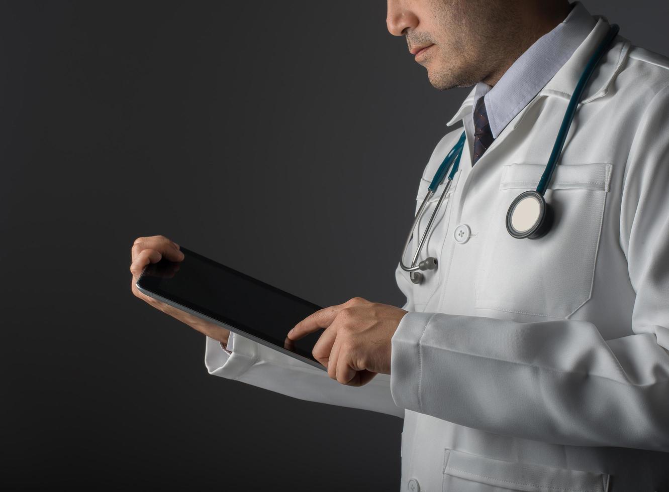 Young medical doctor holding a tablet pc isolated on gray background photo