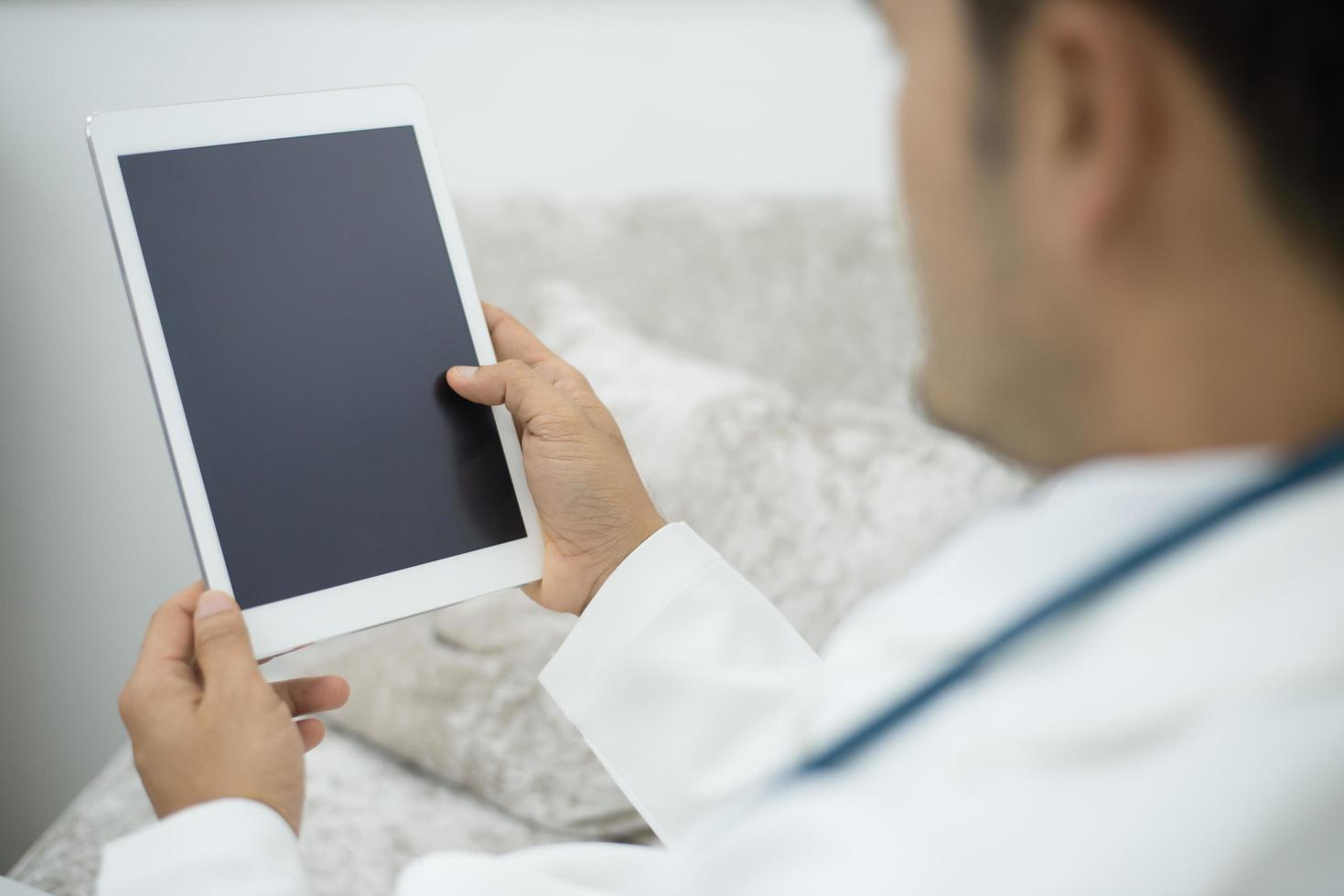 médico en el hospital usando una tableta digital mientras toma un descanso foto