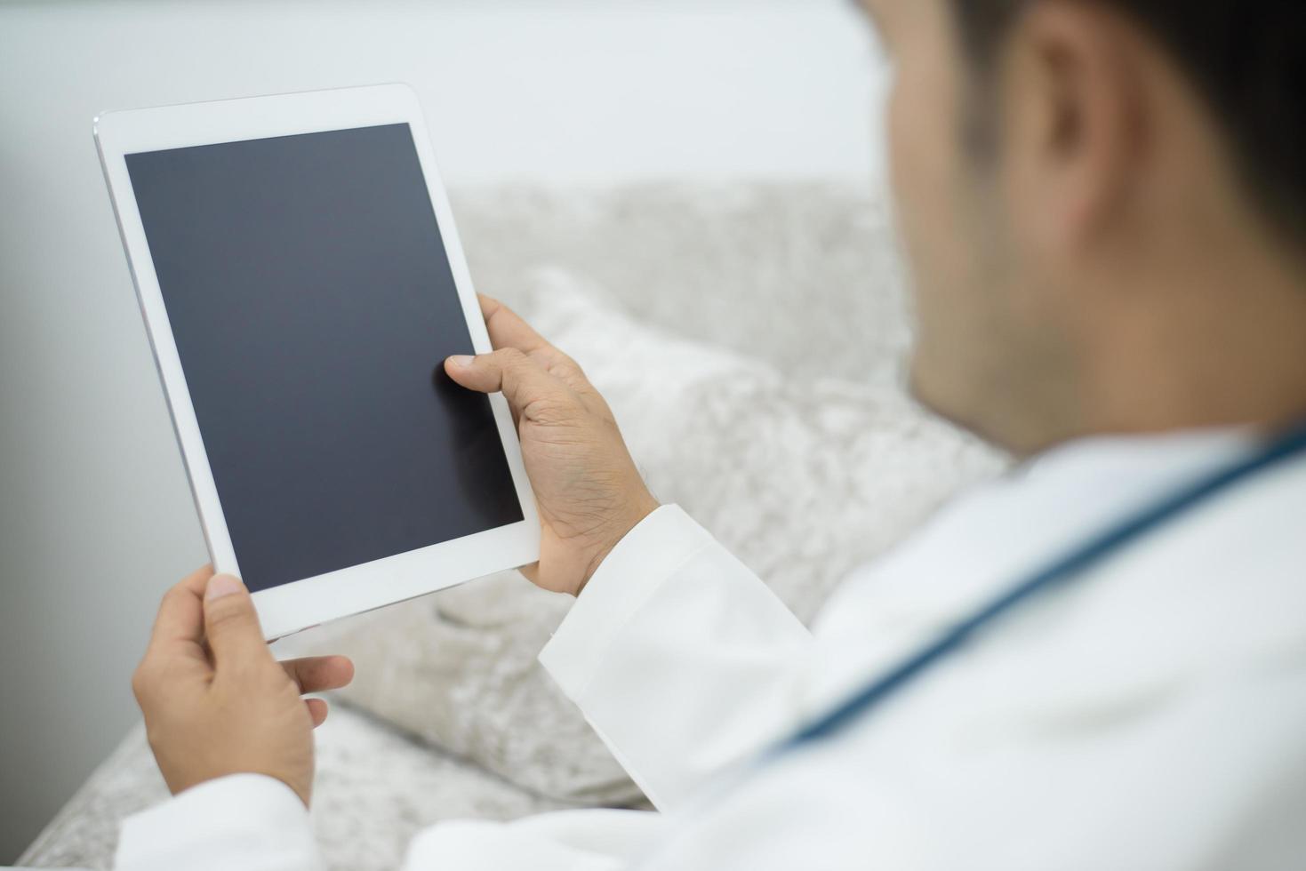 médico en el hospital usando una tableta digital mientras toma un descanso foto
