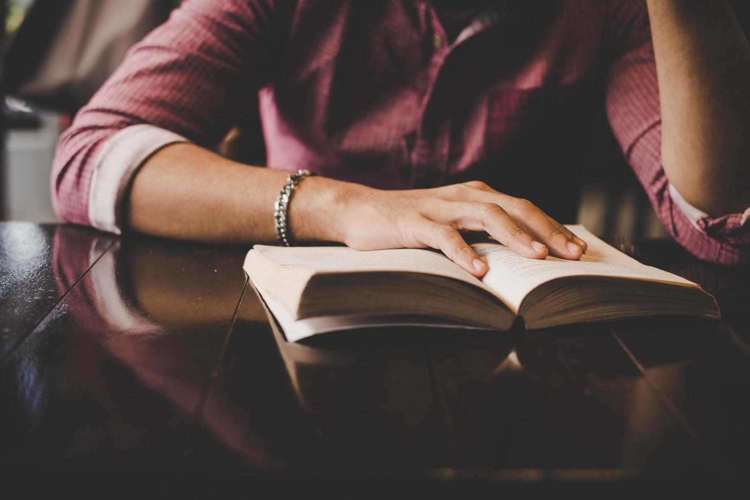 Young bearded hipster reading a book in a cafe photo