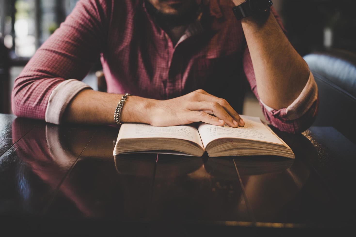 Young bearded hipster reading a book in a cafe photo